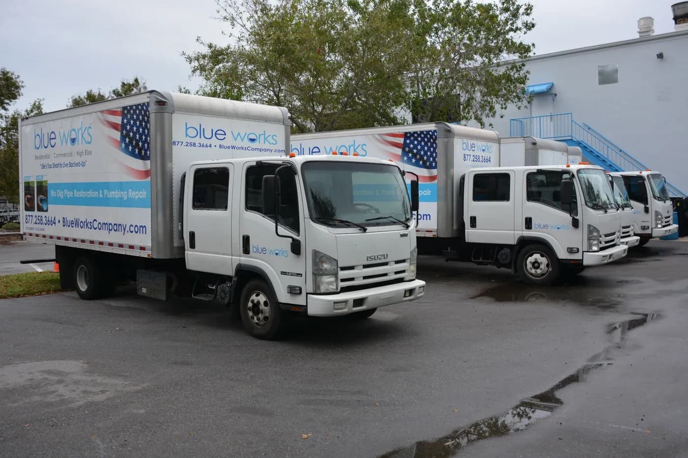 Blue Works service trucks parked outside the company building.