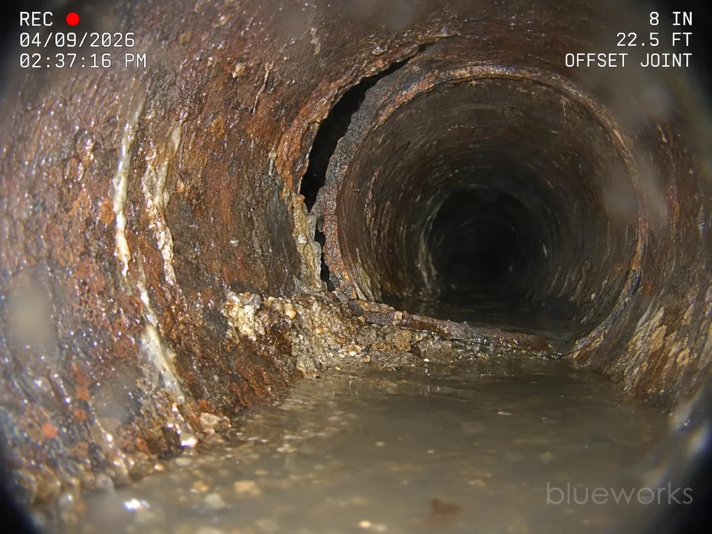 An offset cast-iron joint with sediment and shallow water